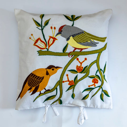 Decorative pillow with bird and floral design on a white background  handmade by women artisans.