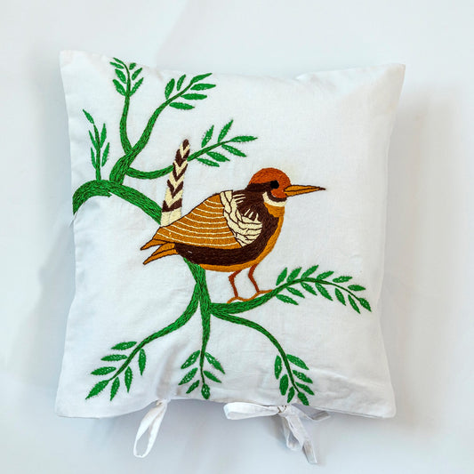 Decorative pillow with embroidered bird and branches on a white background. Handmade  by women artisans.