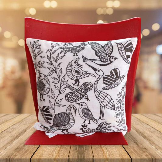 Decorative pillow with bird pattern on white  base  fabric inspired from Gond Art , placed on a wooden surface.
